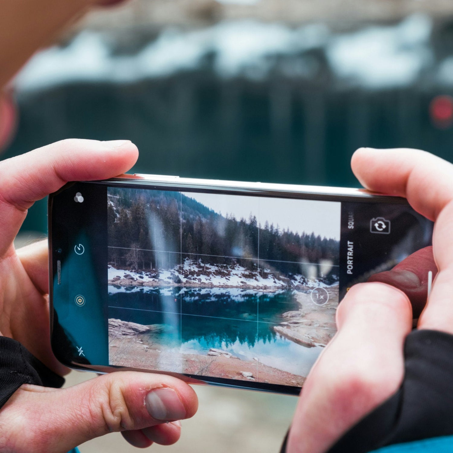 Person Holding a Smartphone Taking a Photo of a Winter Landscape