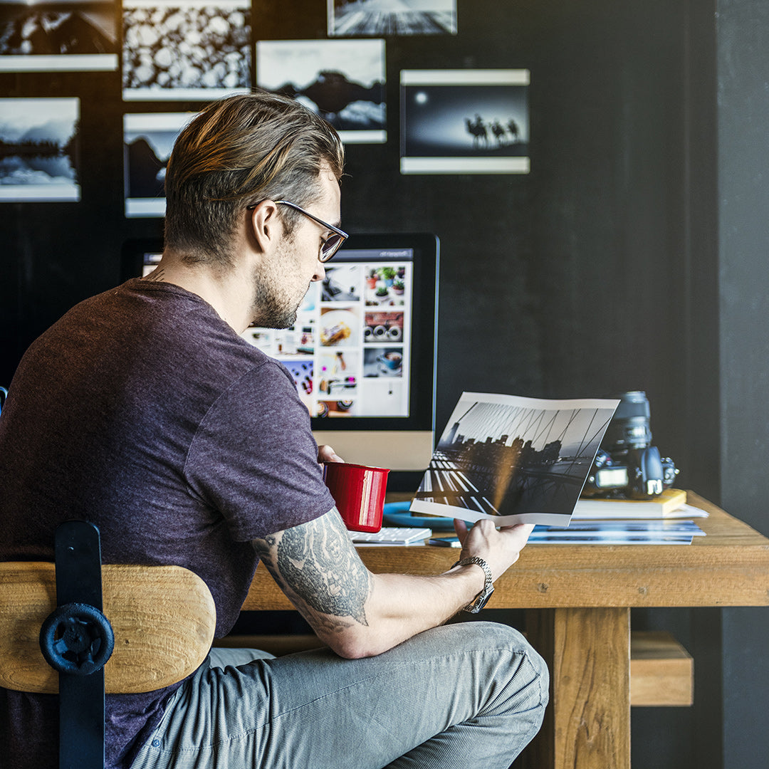 Photographer Looking at Photo Print From His Desk