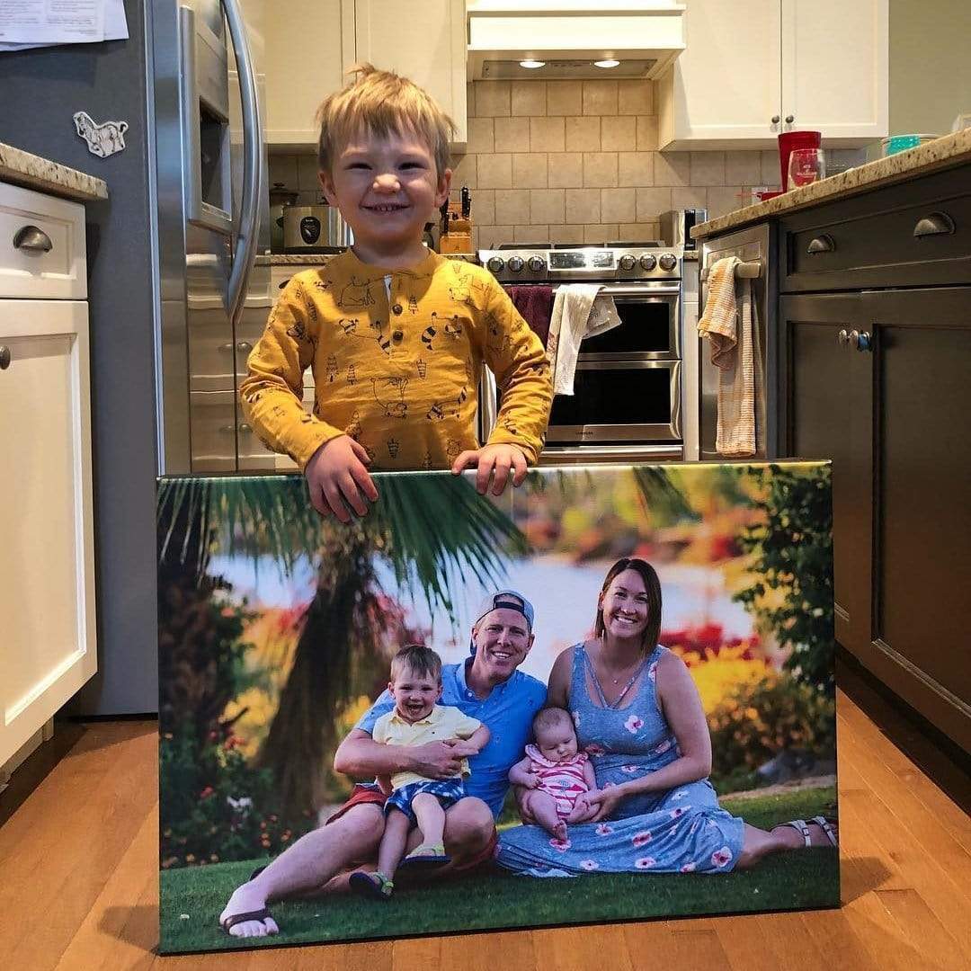 A boy proudly showing off his family photo printed on a Posterjack Canvas Print