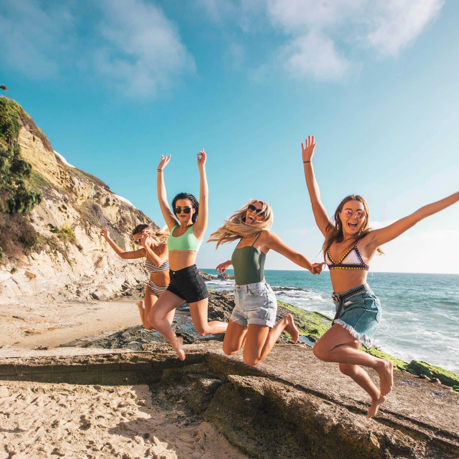 group of friends jumping in the air having fun at the beach