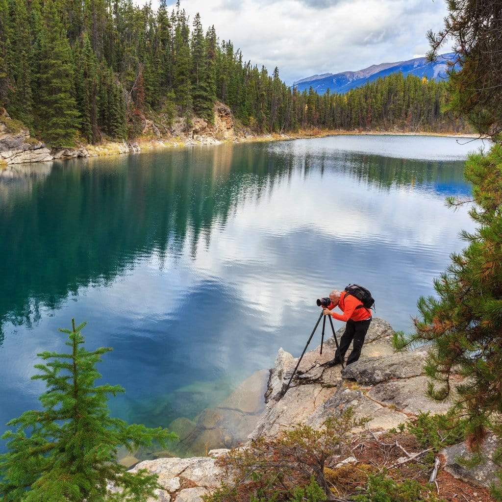 Outdoor Canadian photographer shooting on a lake with mountains in the background